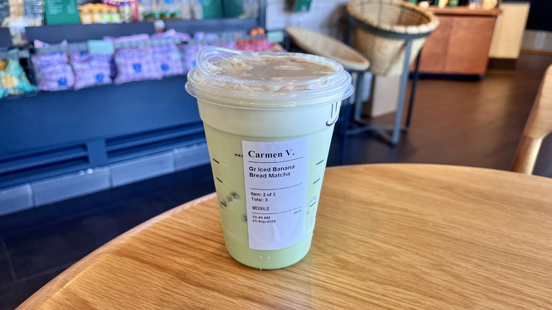 Starbucks Iced Banana Matcha on a table served in a plastic cup featuring its name