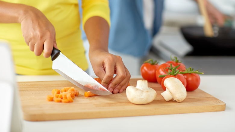 Woman cutting vegetables on board