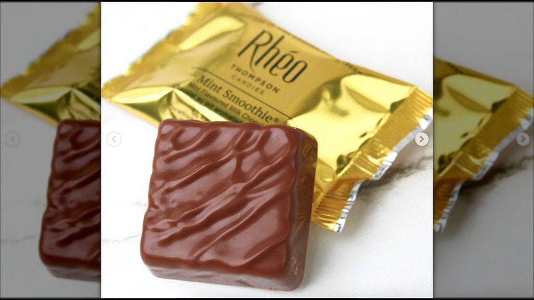 Single square chocolate candy in fornt of gold wrapper