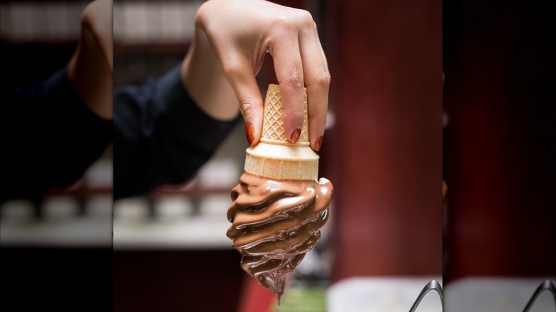 Hand holding a chocolate-dipped ice cream cone upside down
