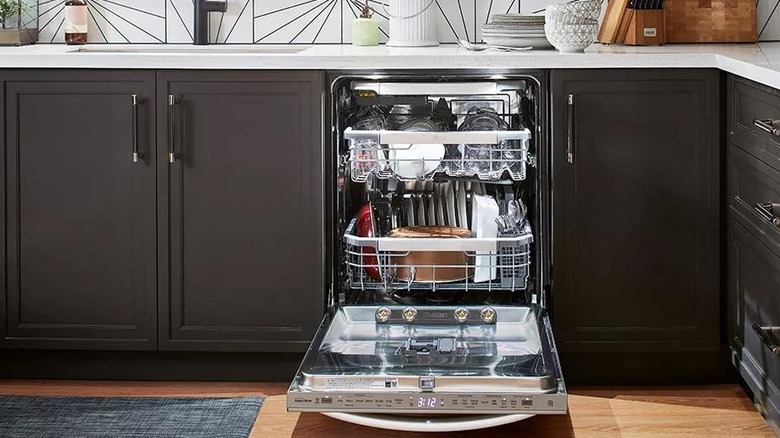 An LG Smart dishwasher open in a kitchen displaying dishes stacked inside