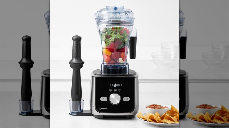 A Vitamix blender stuffed full of vegetables sitting on a counter