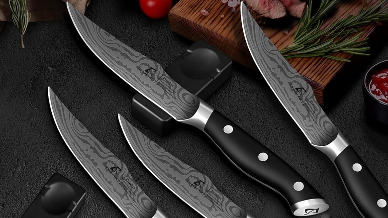 CoquusAid Steak Knives shown on a dark surface surround by rests, a chopping block, and food.