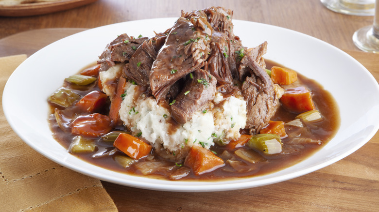 Pot roast served in a plate over mashed potatoes