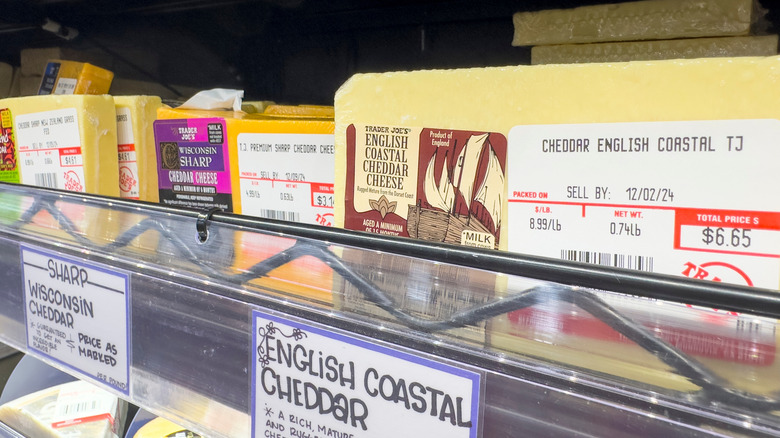 Various cheddar cheeses lining Trader Joe's shelf