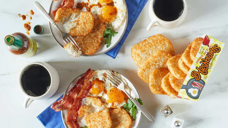 Trader Joe's hash browns served alongside hot sauce, coffee, bacon, and eggs on table