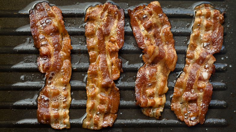 Bacon slices cooking in frying pan