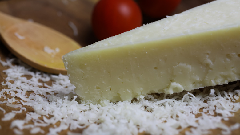 Close up of wedge of pecorino cheese with some grated