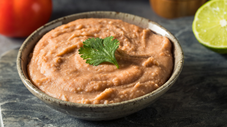 Bowl of refried beans, garnished with cilantro leaf