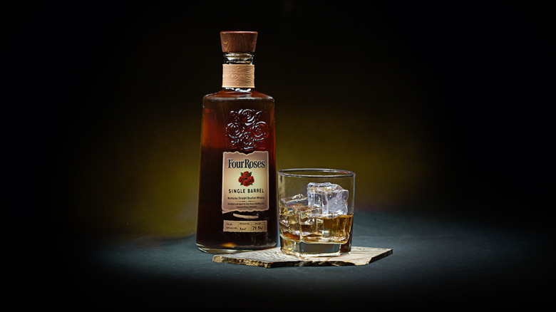 A stylized product shot of a bottle of Four Roses Single Barrel next to a filled glass