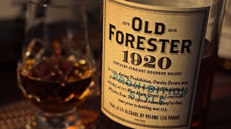 A close up of a bottle of Old Forester 1920 showcasing its label next to a filled glass
