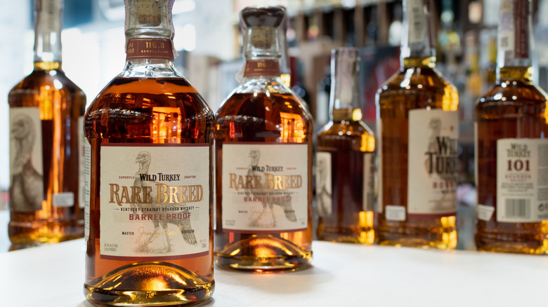 Two bottle of Wild Turkey Rare Breed shown on a table with blurred bottles in the background