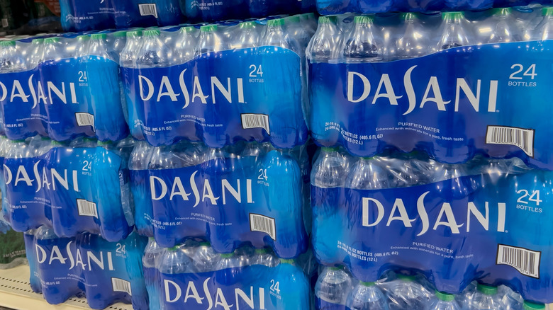 Several large 24-bottle packs of Dasani water in a store.