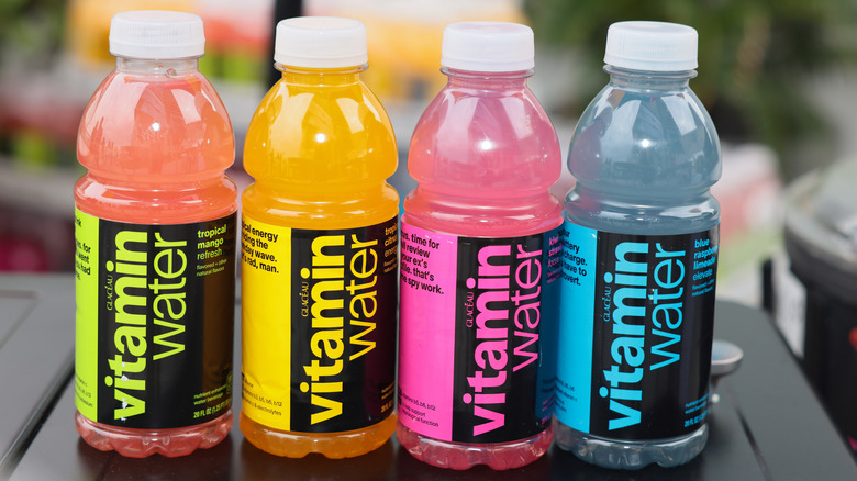 Four bottles of Vitamin Water in different colors and flavors on a table.