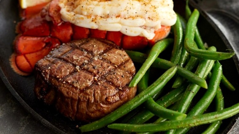 Black Angus steakhouse grilled filet mignon with lobster tail and green beans on plate