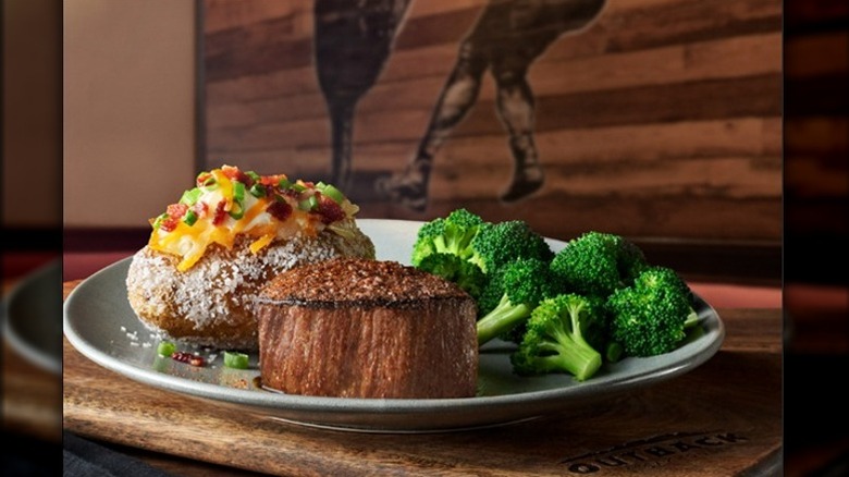 Outback Steakhouse filet mignon with broccoli and loaded baked potato on plate
