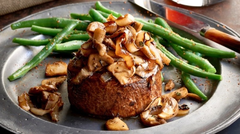 Saltgrass Steakhouse smother filet mignon with onions and mushrooms and a side of green beans on plate