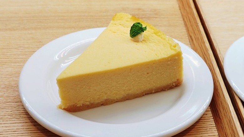 A single slice of lemon cheesecake on a white plate
