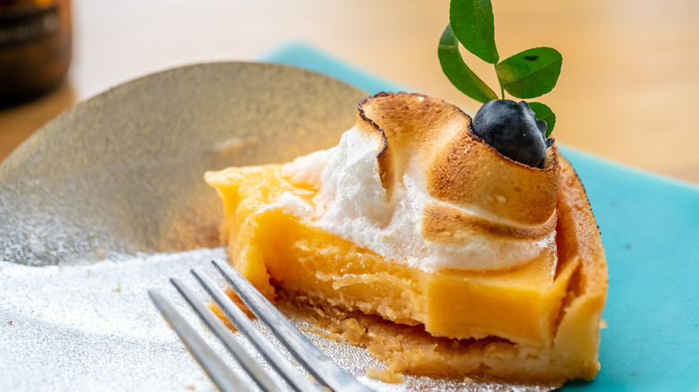 A single slice of lemon meringe pie with a fork taken out of it
