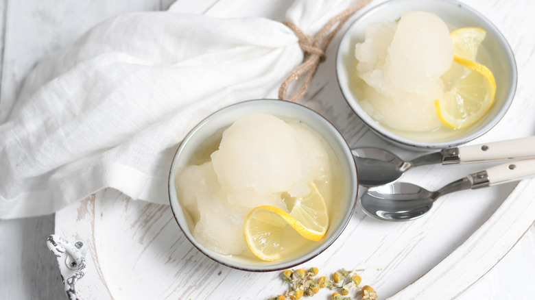 Two white bowls with scoops of lemon sorbet as well as lemon slices