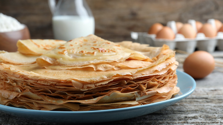 stack of crepes on plate near eggs