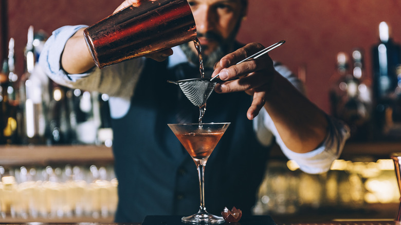 bartender pouring strained drink