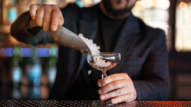 bartender adding ice to cocktail glass