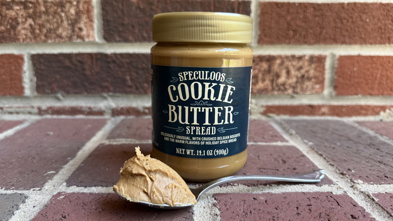 Jar of Trader Joe's speculoos cookie butter spread behind spoonful of extra-thick cookie butter on brick surface