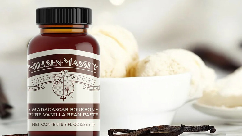 Bottle of Nielsen-Massey Vanilla Bean Paste next to vanilla bean and bowl of vanilla ice cream