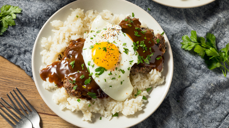 Plate of Hawaiian loco moco with rice, beef patties, gravy, and fried egg