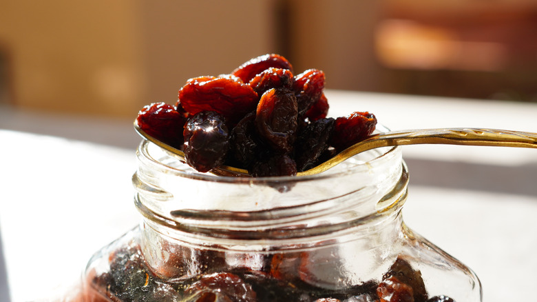 Raisins soaked in rum on a spoon above a jar