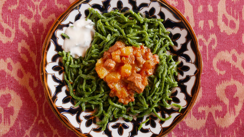 A plate of shivit oshi, green noodles topped with beef stew and tangy yoghurt