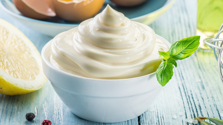 A white dipping bowl of mayo with some garnishes