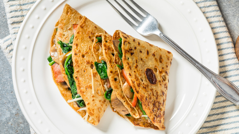 Two savory crepes folded into triangles on a white plate