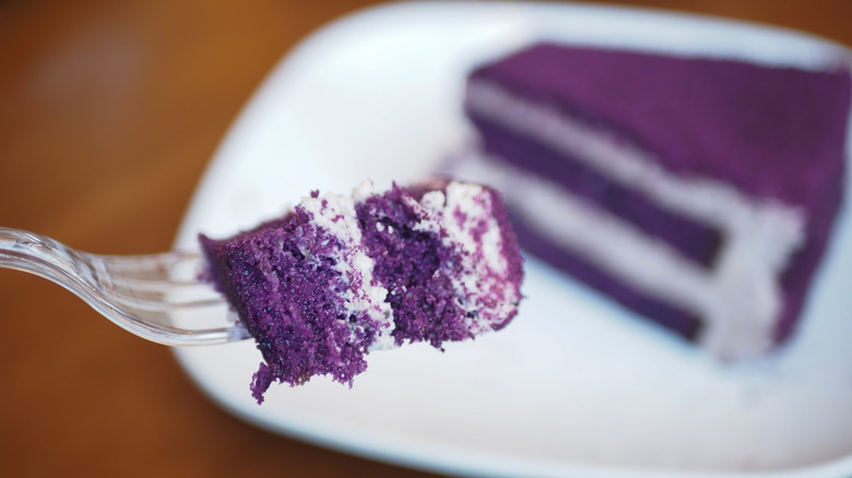 A slice of ube cake with a close up on a fork of it