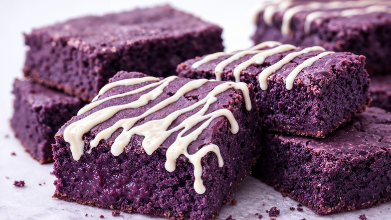 Several squares of ube brownies, some with white frosting