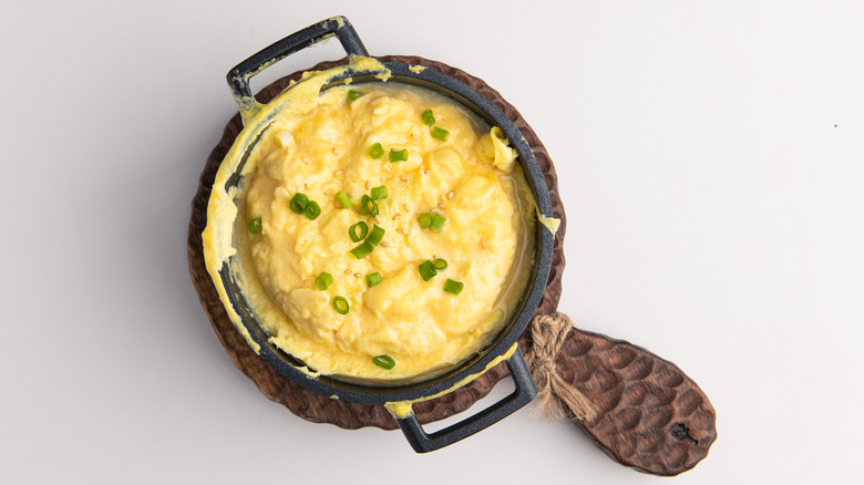 Bowl of creamy scrambled eggs in skillet