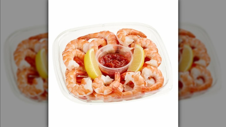 Kirkland Signature shrimp cocktail with cocktail sauce and lemon in a plastic container.