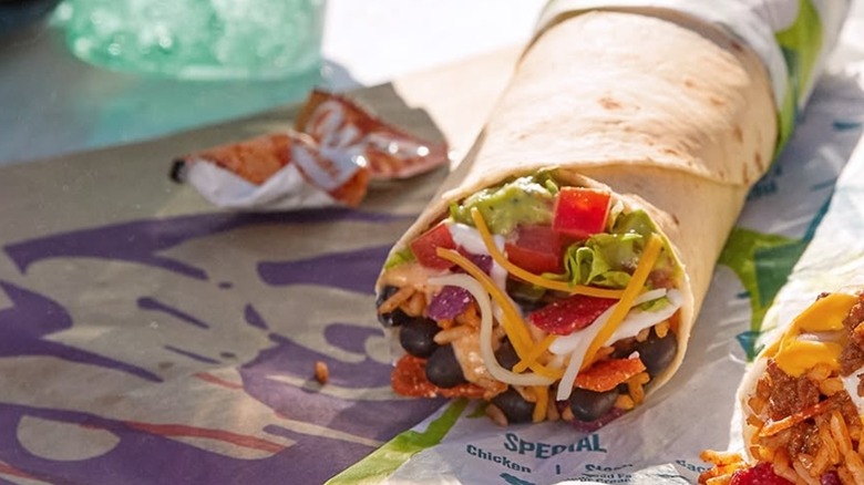 Fiesta veggie burrito next to sauce, drink, and another burrito