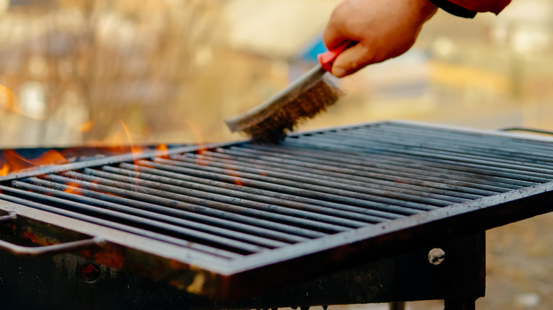 Man cleaning a grill with a grill brush