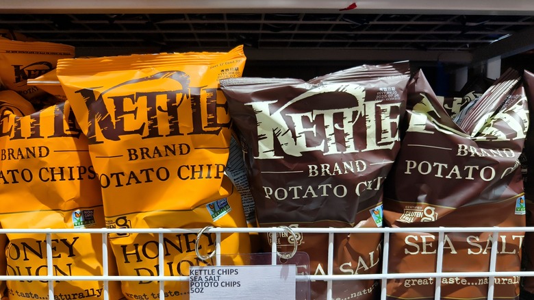 Kettle Brand Potato Chips in Sea Salt and Honey Dijon varieties displayed in colorful packaging on a store rack