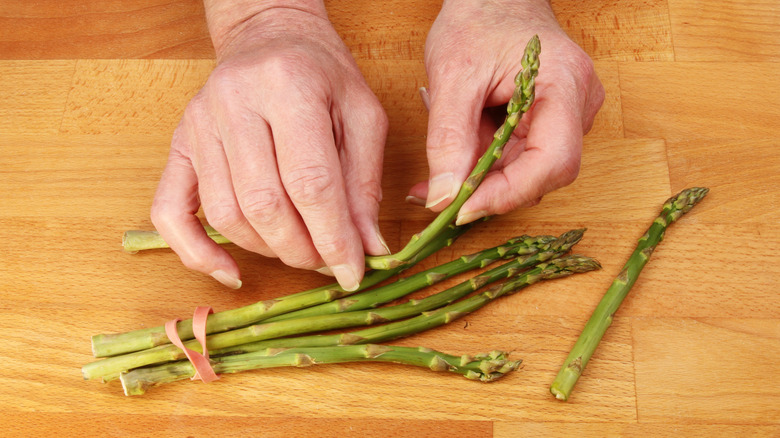 Person preparing asparagus by snapping the stocks