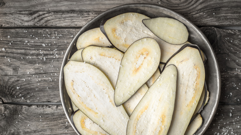 Bowl of sliced salted eggplant ready to sweat
