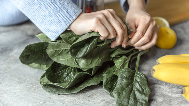 Woman preparing dark leafy greens on a kitchen countertop