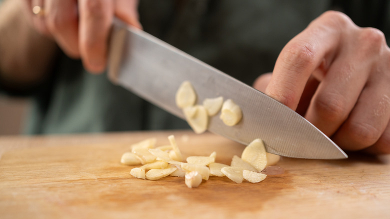 Chef chopping garlic on a cutting board