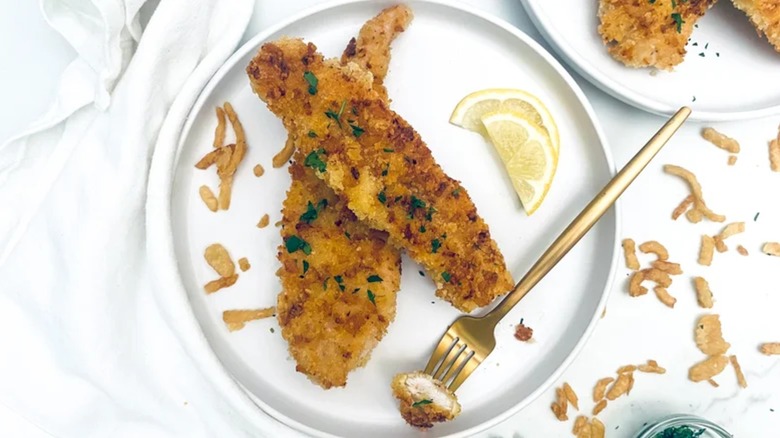 Chicken tenders on white plate with lemon slices