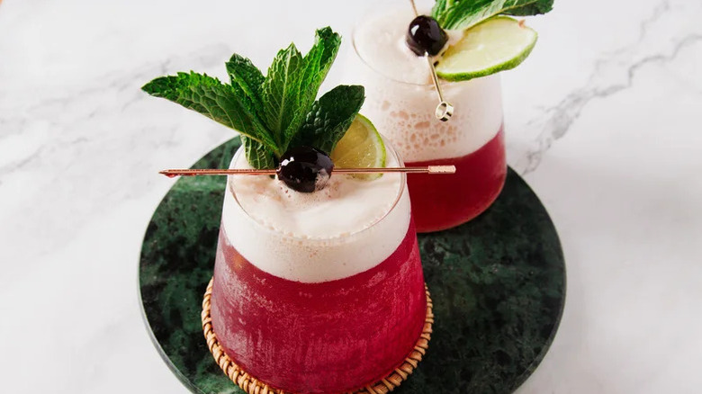 Frozen Shirley Temples with mint and cherry garnish against marble background.