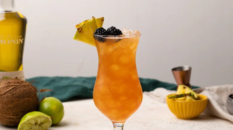 Rum Runner in a hurricane glass with pineapple and blackberry garnish.