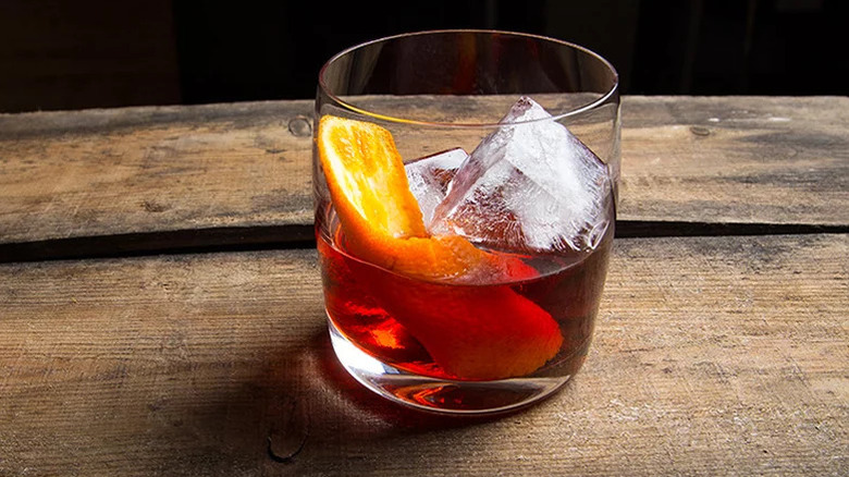 Negroni on wooden table against dark background.