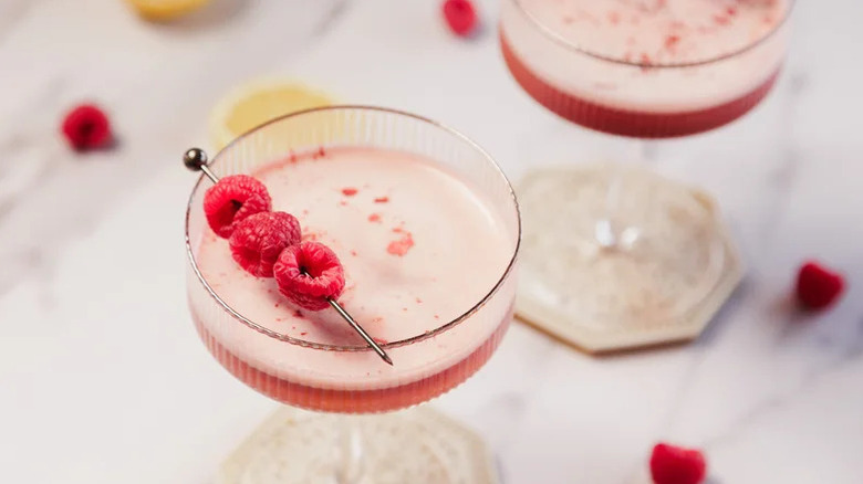 Close up aerial of raspberry martini with fruit garnish.